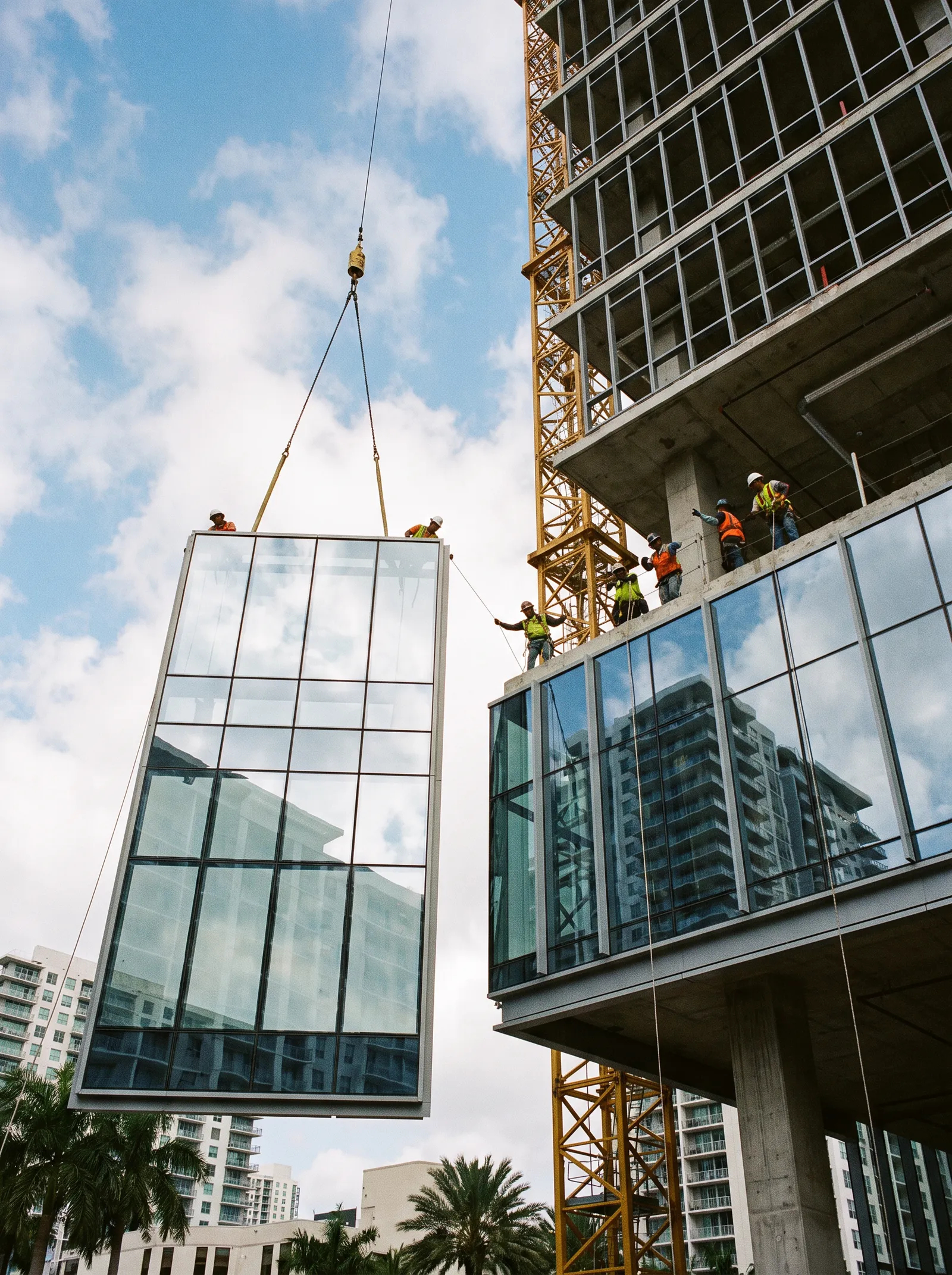 A curtain wall glass panel lifted by crane onto an upper floor